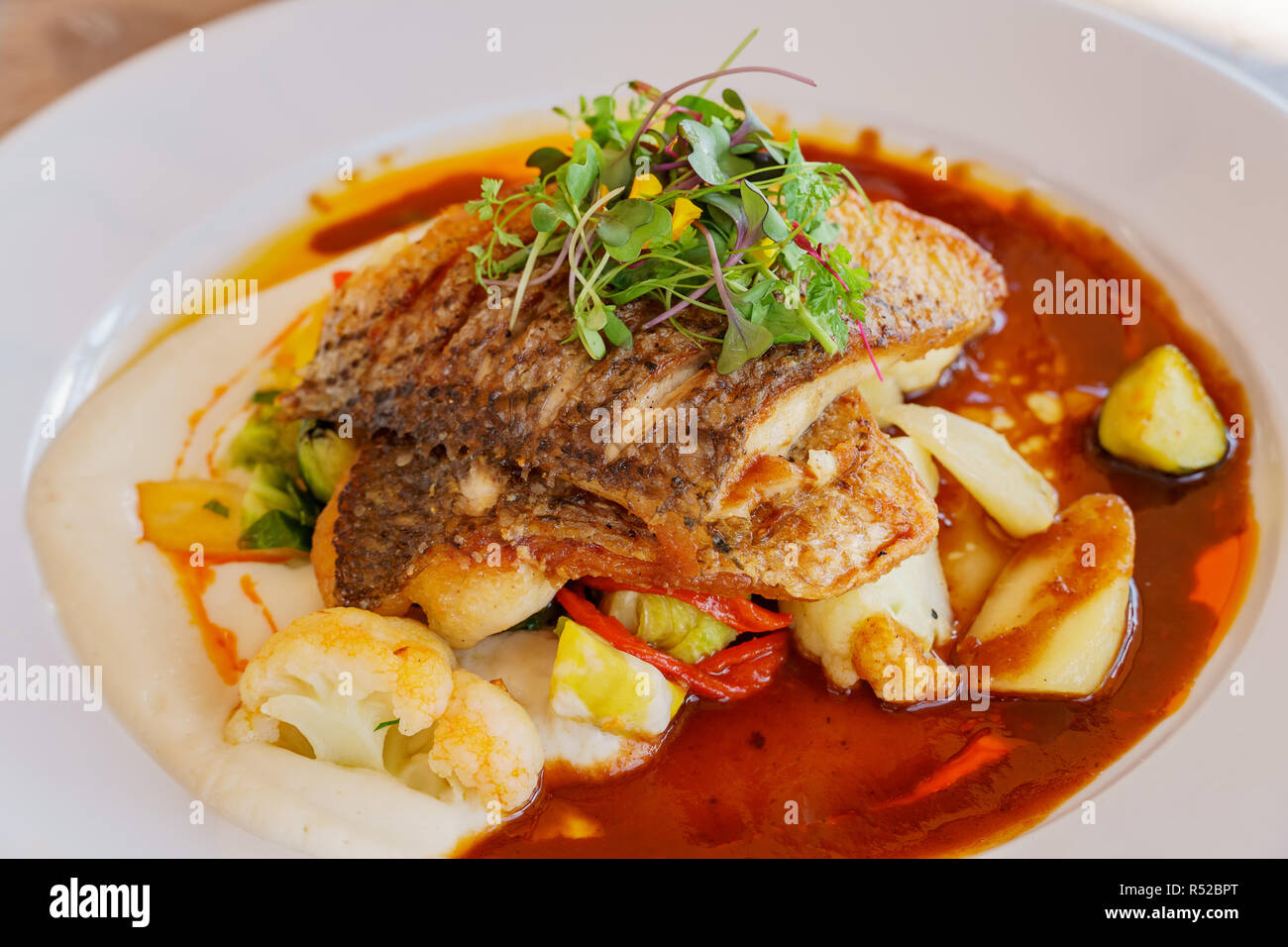 Nahaufnahme von gebratener Seebarsch, Dienen mit Blumenkohl dazugeben und Sauce, aßen in Laguna Beach, Kalifornien Stockfoto