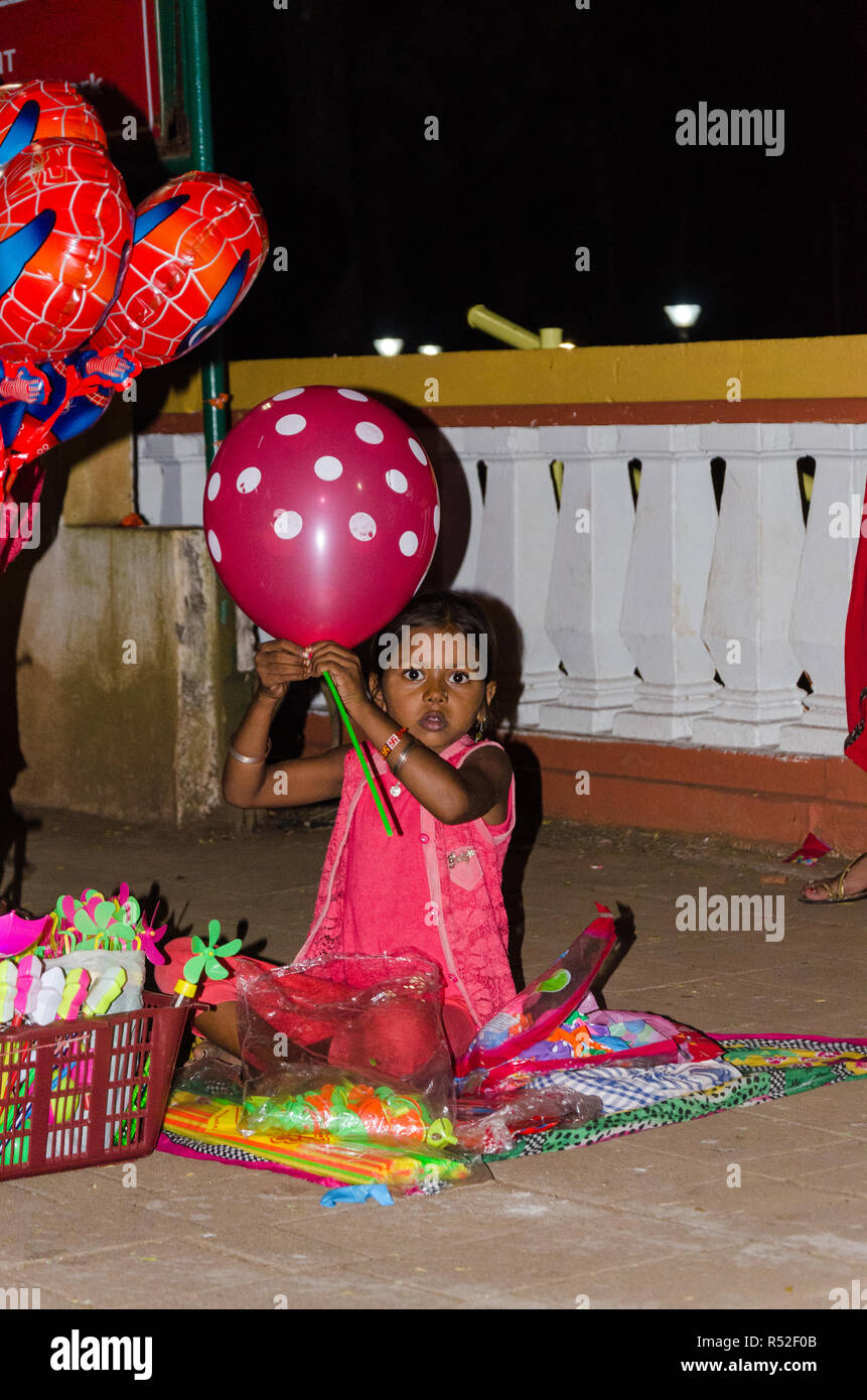 Ein sehr junges Mädchen Kind Verkauf von Ballons auf dem Fußweg während des 49. Internationalen Film Festival von Indien in Panaji, Goa, Indien. Stockfoto