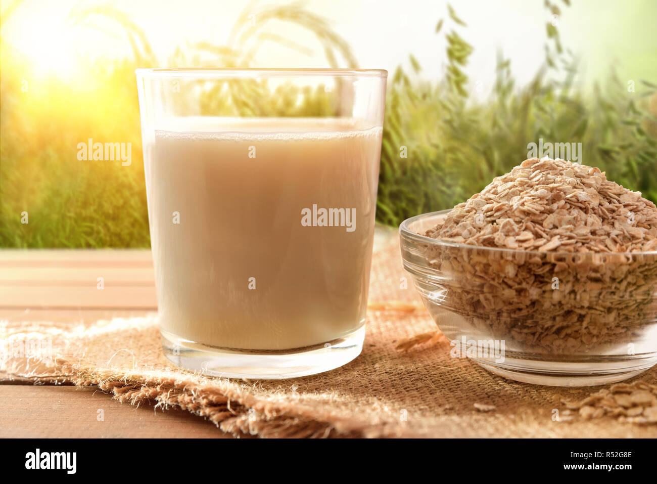 Oat Drink in Glas und Getreideflocken auf Holz Tisch in der Natur. Horizontale Komposition. Ansicht von vorn Stockfoto