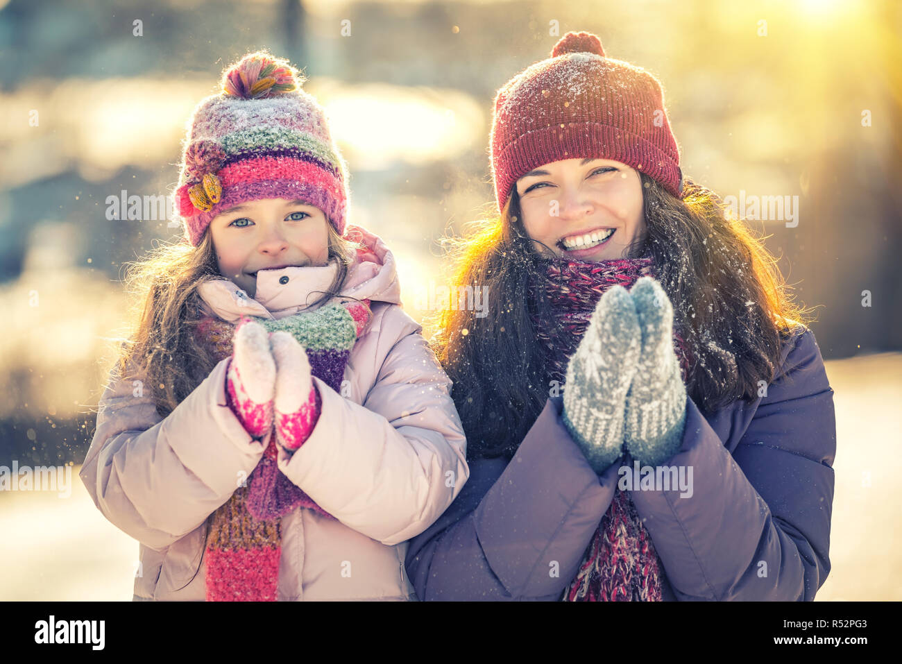 Kleine Mädchen und ihre Mutter spielen im Freien an sonnigen Wintertag Stockfoto