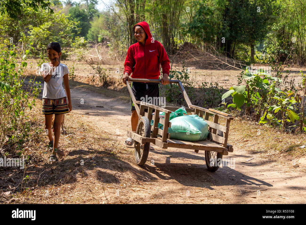 Don Daeng, Laos - April 27, 2018: Lokale Mutter und Tochter Transport landwirtschaftlicher Güter auf einer hölzernen Warenkorb Stockfoto