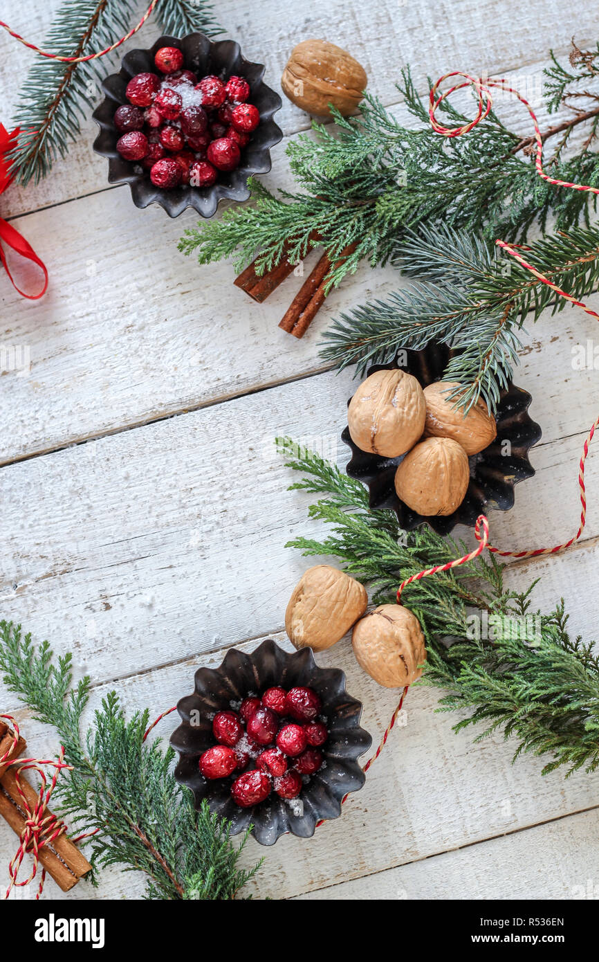 Weihnachtliche Stimmung flatlay mit roten Beeren, Nüsse, Zimtstangen und Evergreens auf weißem Hintergrund Holz, flach Stil Stockfoto