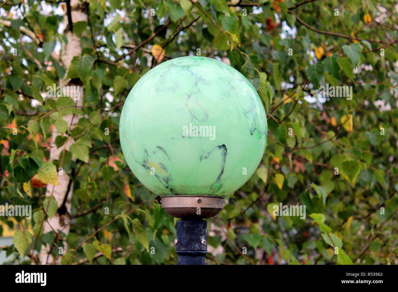 Licht aus grünem Marmor wie Textur runde Straßenlaterne auf Metall Pol auf frische grüne Blätter Hintergrund an warmen Sommertagen montiert Stockfoto