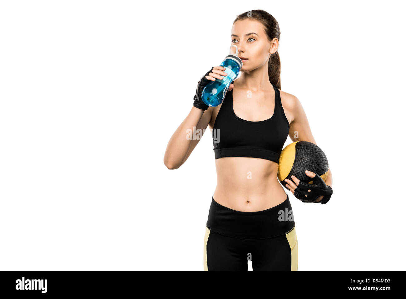 Schöne Sportlerin Trinkwasser aus Sport Flasche und Holding Medizinball isoliert auf weißem Stockfoto