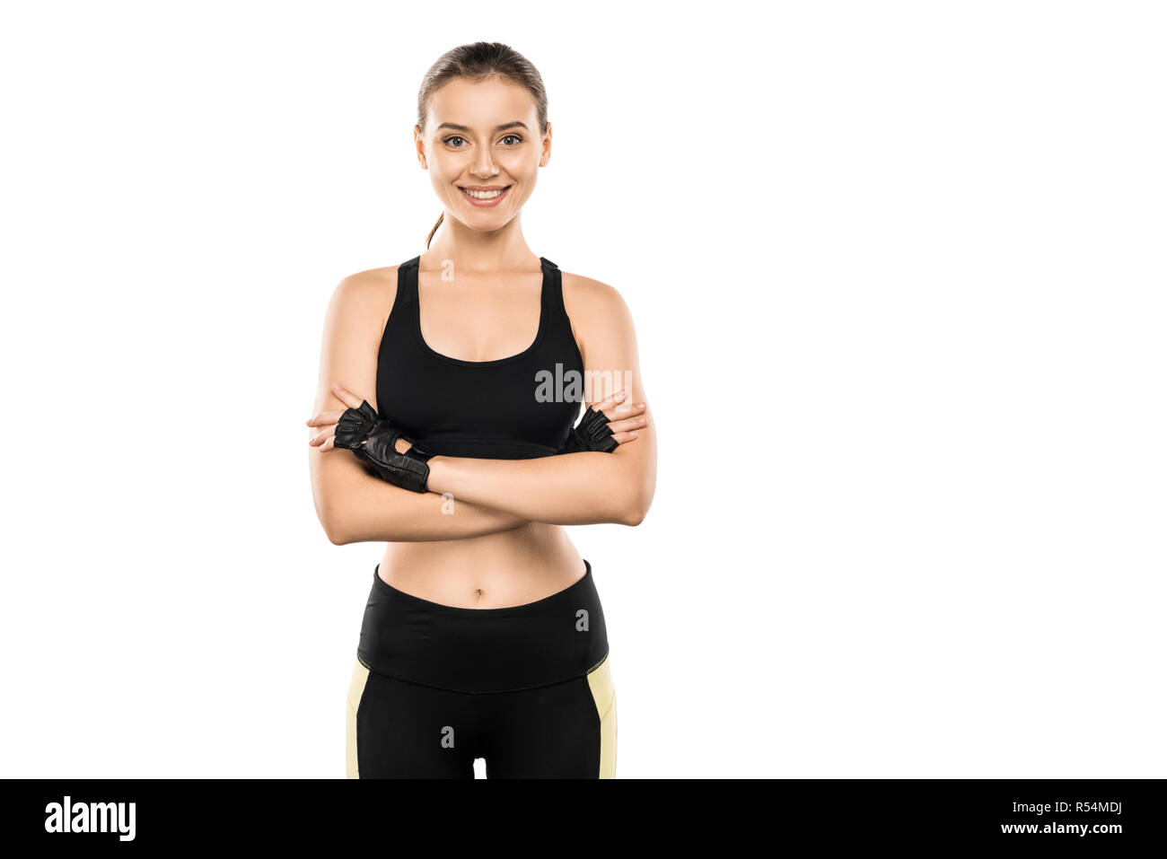 Lächelnd Sportlerin im Gewichtheben Handschuhe mit verschränkten Armen auf Kamera isoliert auf weißem Stockfoto