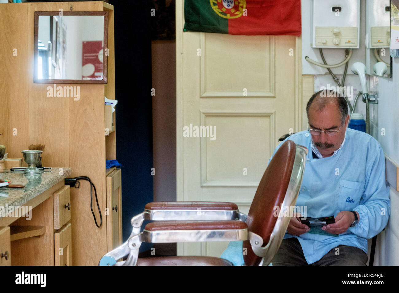 Ein Friseur ist und wartet auf seine nächste Client in seinem kleinen Salon in Coimbra, Portugal Stockfoto