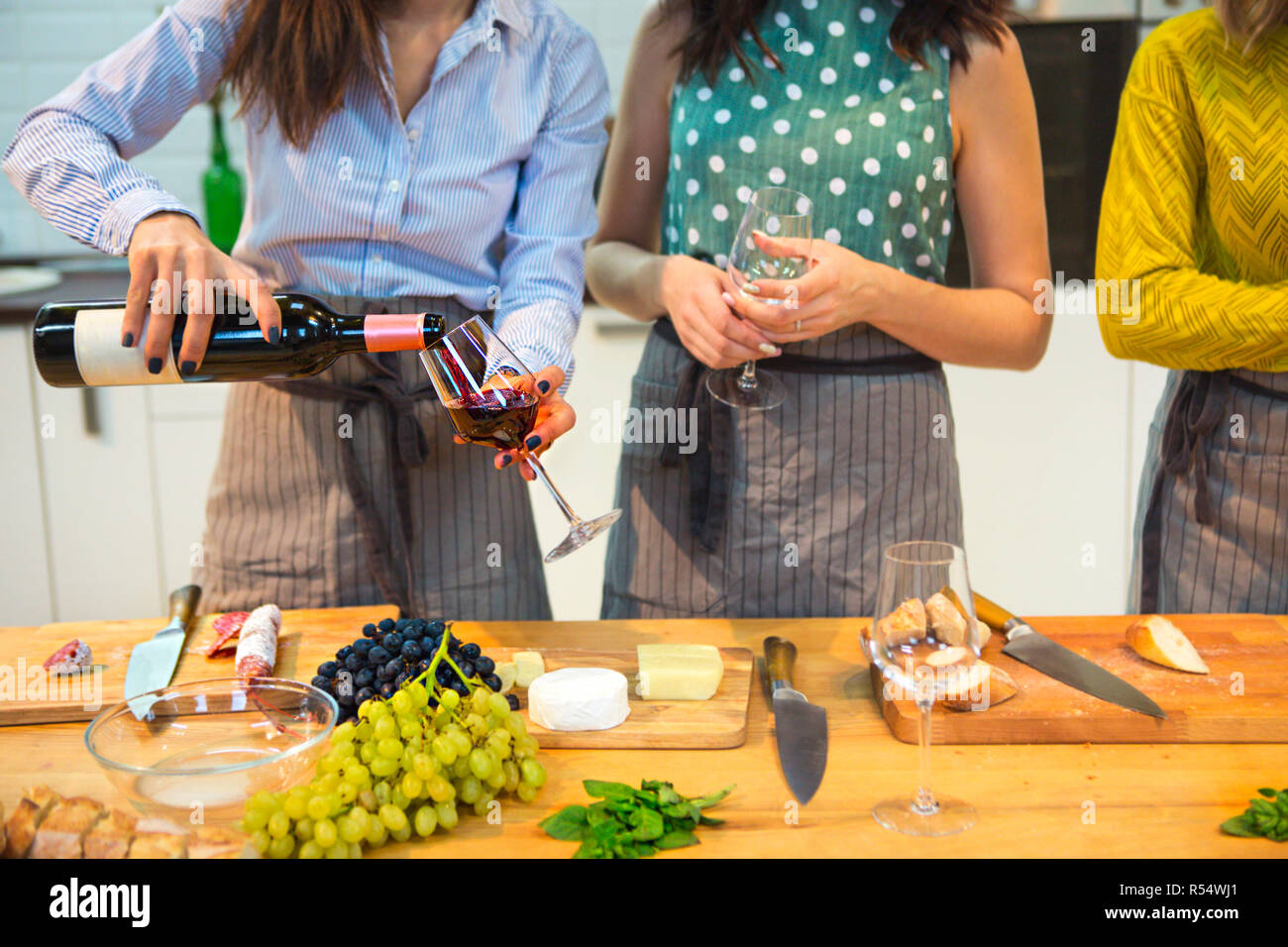 Freundliche weibliche Freunde Vorbereitung einer Mahlzeit zusammen und trinken Rotwein in der Küche Stockfoto