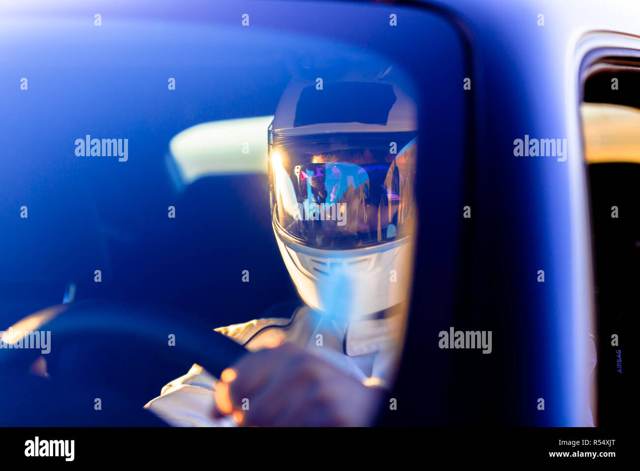 Ein Rennfahrer das Tragen eines Helmes am Steuer seines Fahrzeugs an einem sonnigen Morgen im Anschluss Stockfoto