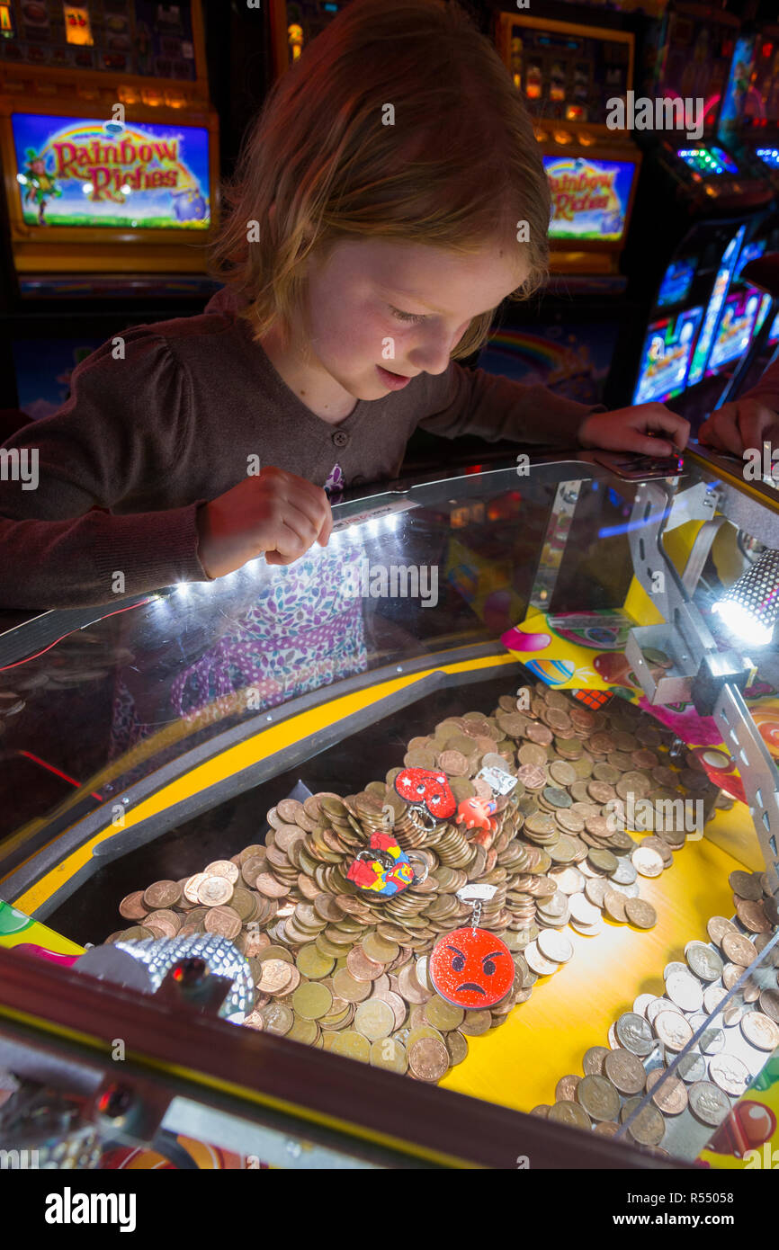 Junge Mädchen im Alter von 8 Jahren/Alter ab 8 Jahren das Spielen auf einem beliebten traditionellen Coin Pusher/drücken, Münzen Spiel in pier Fun House Arcade. UK. (98). Stockfoto