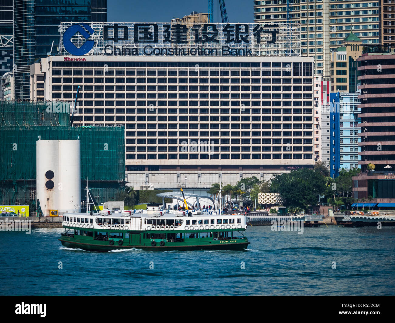 China Construction Bank Hongkong China - Star Ferry fährt vor der großen China Construction Bank Werbung auf der Kowloon-Seite des Victoria Harbour Stockfoto