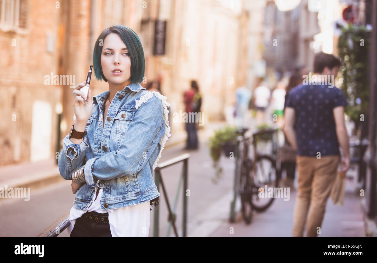 Porträt einer jungen Frau rauchen eine elektronische Zigarette auf der Straße Stockfoto