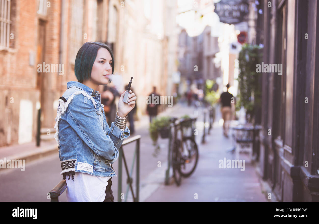 Porträt einer jungen Frau rauchen eine elektronische Zigarette auf der Straße Stockfoto