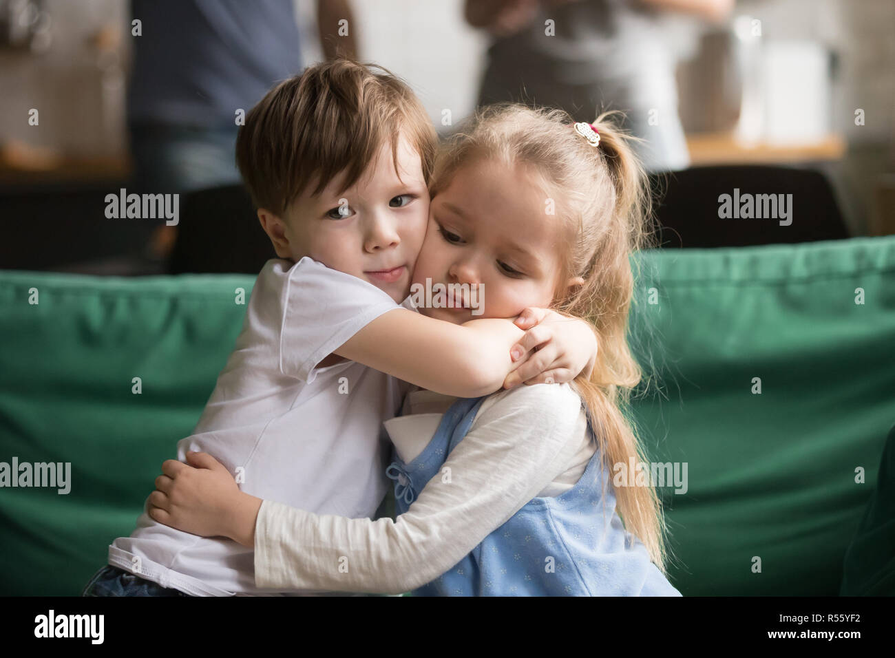 Kleiner Bruder umarmen umgekippt Schwester saß auf der Couch Stockfoto