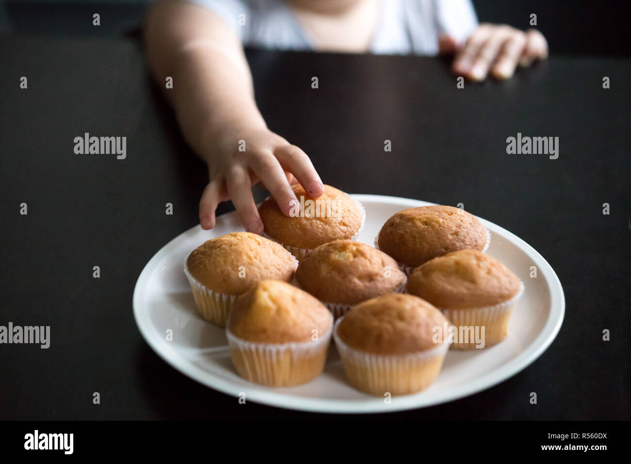 Hand des Kindes, die Muffins auf Tisch Nahaufnahme Stockfoto