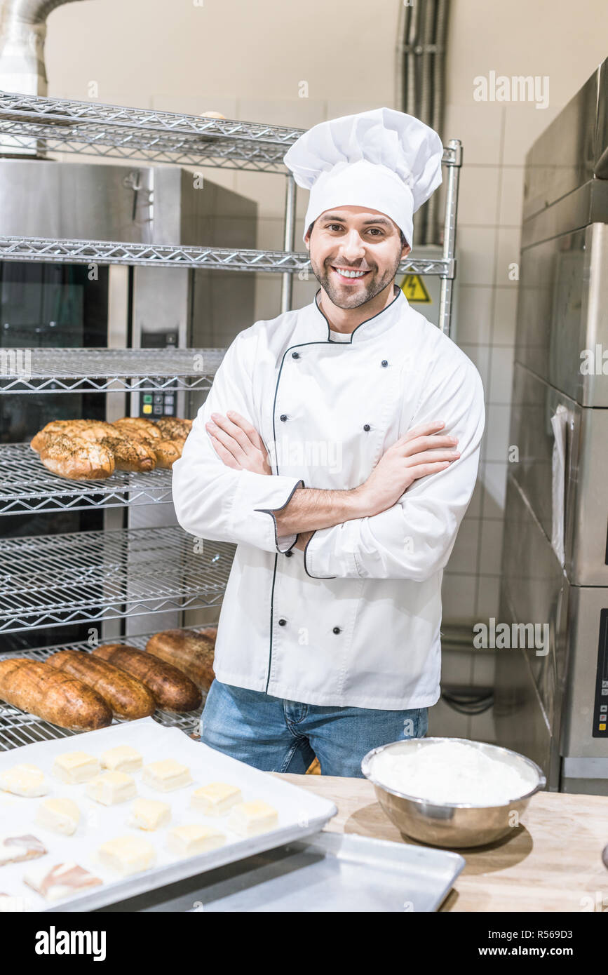 Lächelnd männlichen Bäcker Stehen mit gekreuzten Armen Küche Stockfoto