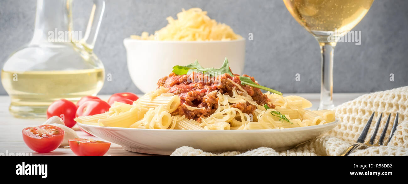 Italienische Pasta Bolognese Penne rigatone Hackfleisch in Tomatensoße und Parmesan. Noch immer leben auf weiße Holztisch mit Cherry Tomaten serviert, Stockfoto