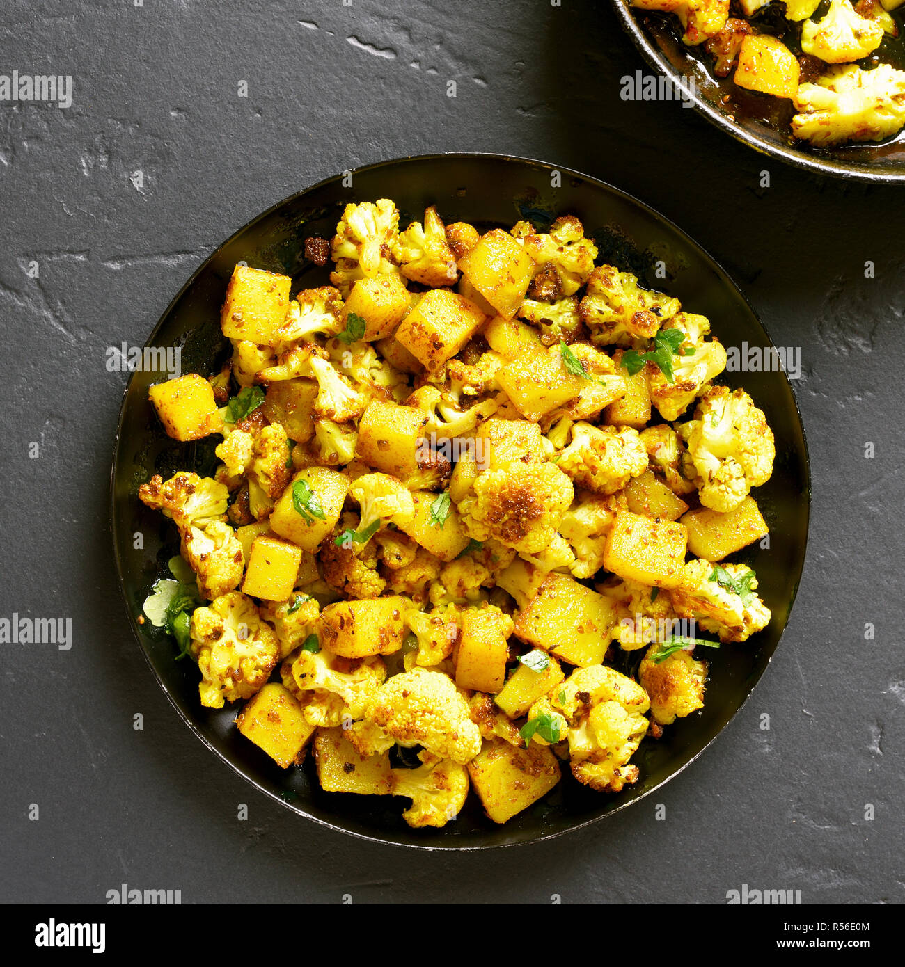 Nahaufnahme von Aloo Gobi indische Gericht. Gebratener Blumenkohl mit Kartoffeln auf schwarzen Stein Hintergrund. Ansicht von oben Stockfoto