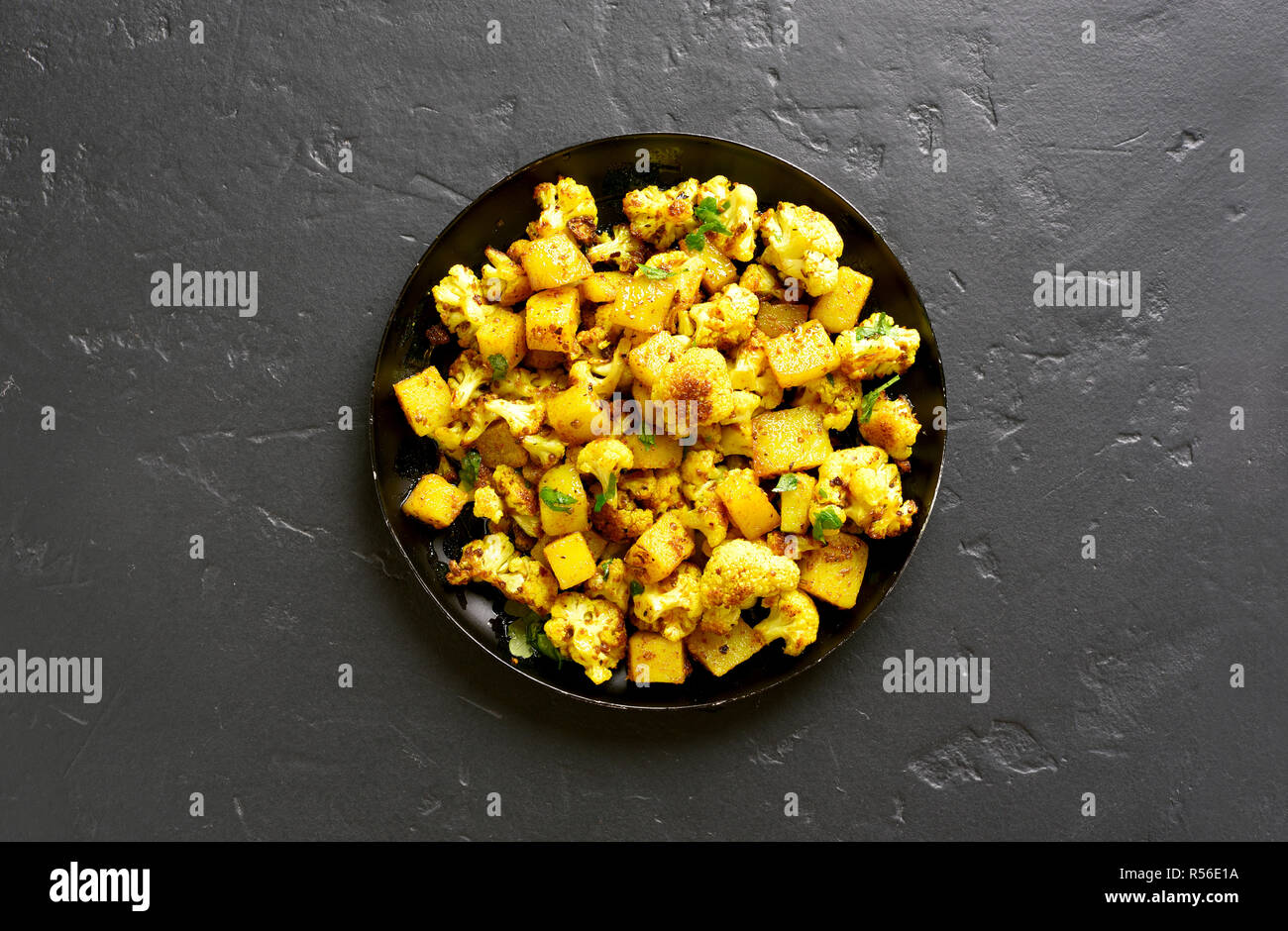 Aloo Gobi indische Gericht. Gebratener Blumenkohl mit Kartoffeln auf schwarzen Stein Hintergrund mit kopieren. Ansicht von oben Stockfoto