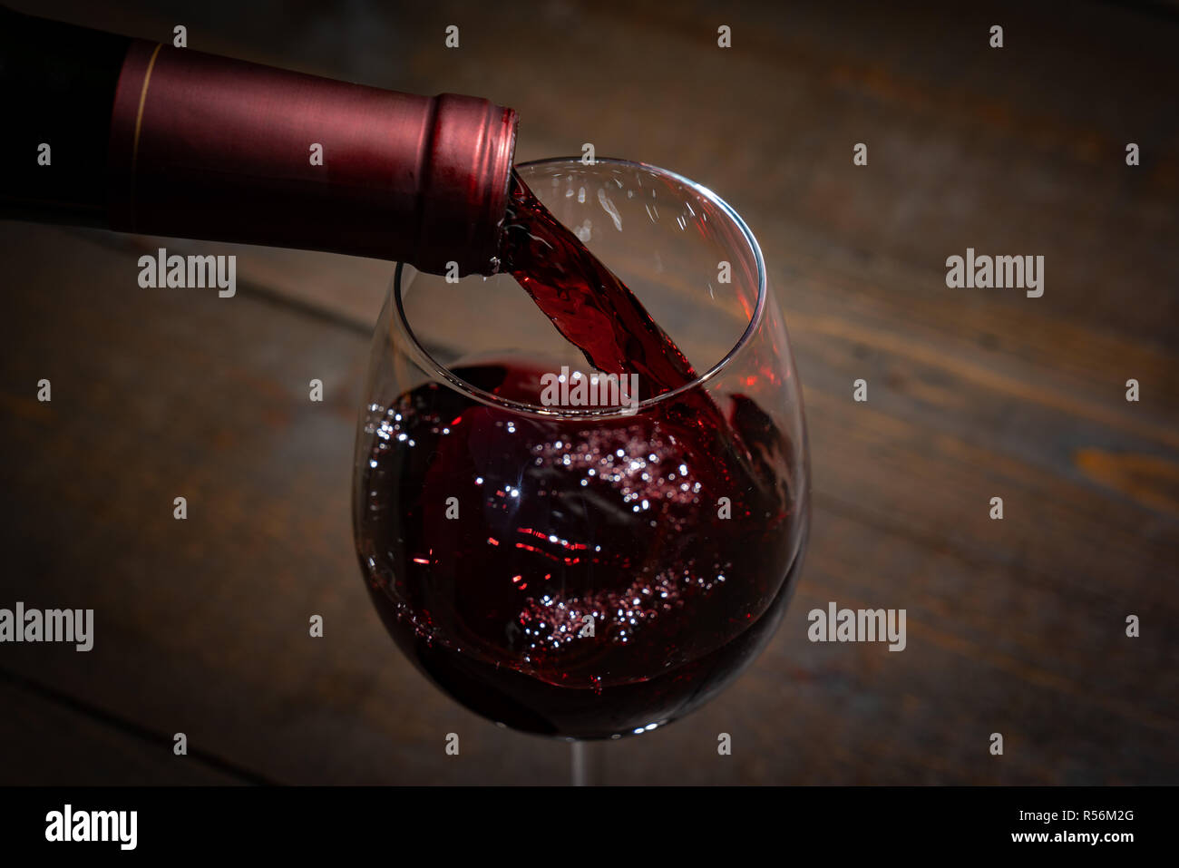 Rotwein Gießen in einem Weinglas aus der Flasche Stockfoto