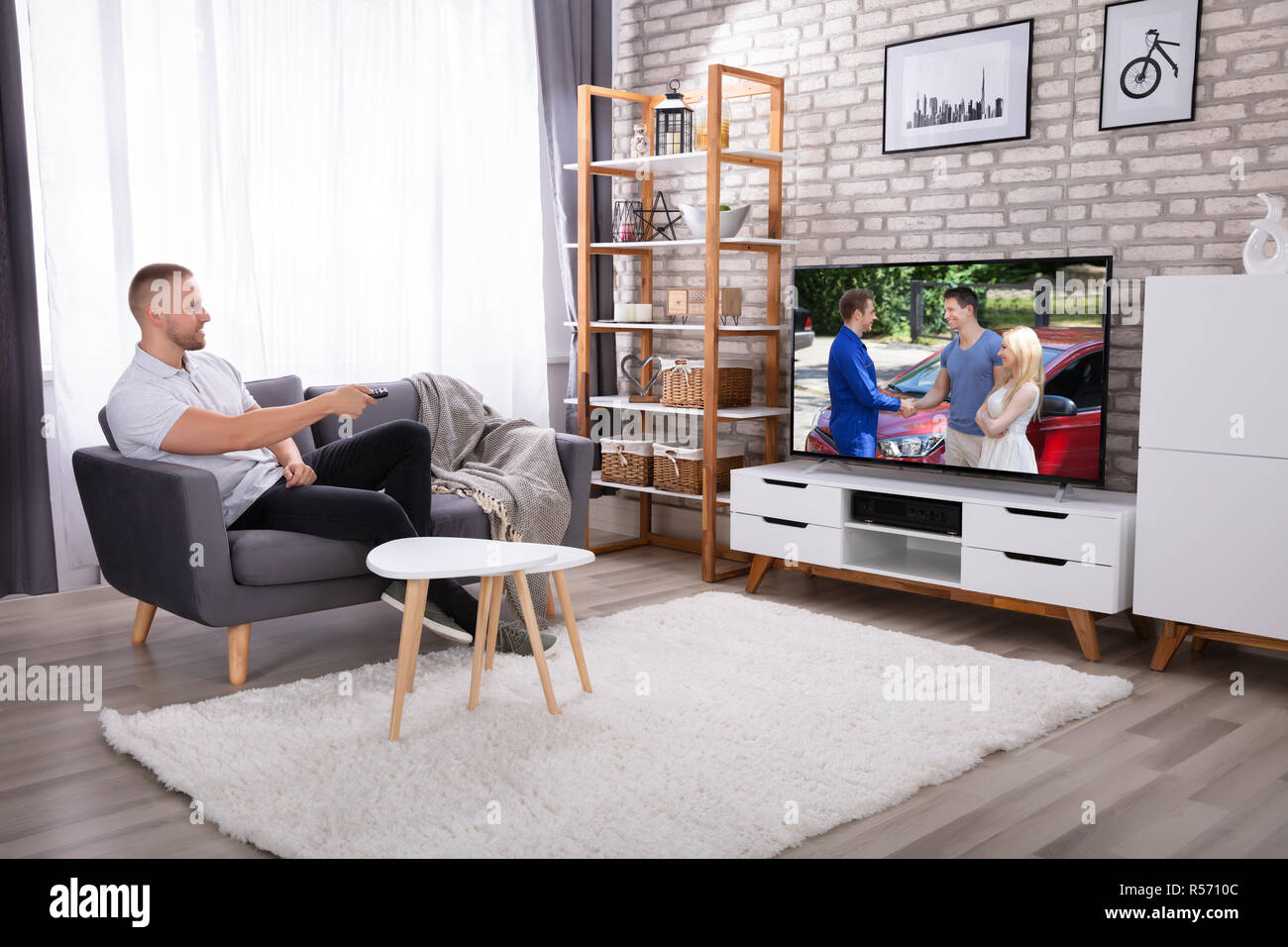 Mann sitzt auf einem Sofa Fernsehen zu Hause beobachten Stockfoto