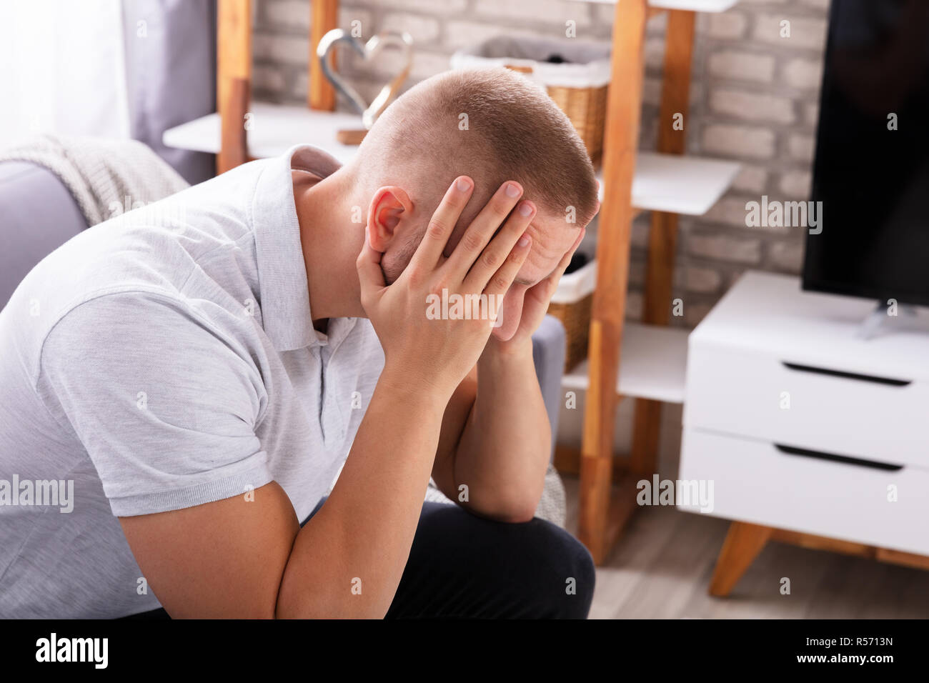 Seitenansicht eines umgekippten Junge Mann sitzt auf einem Sofa Stockfoto