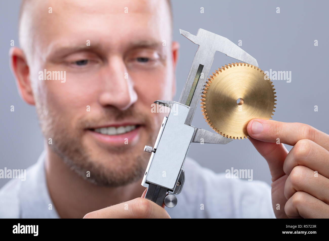 Close-up von der Größe eines Menschen Messgetriebe mit digitalen elektronischen Messschieber auf grauem Hintergrund Stockfoto