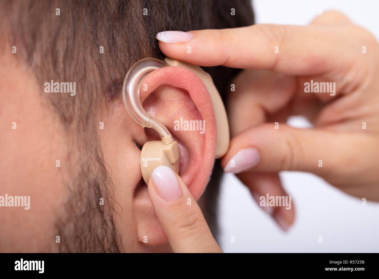 In der Nähe von einem Arzt Hand einfügen Hörgerät im Ohr des Männlichen Patienten Stockfoto