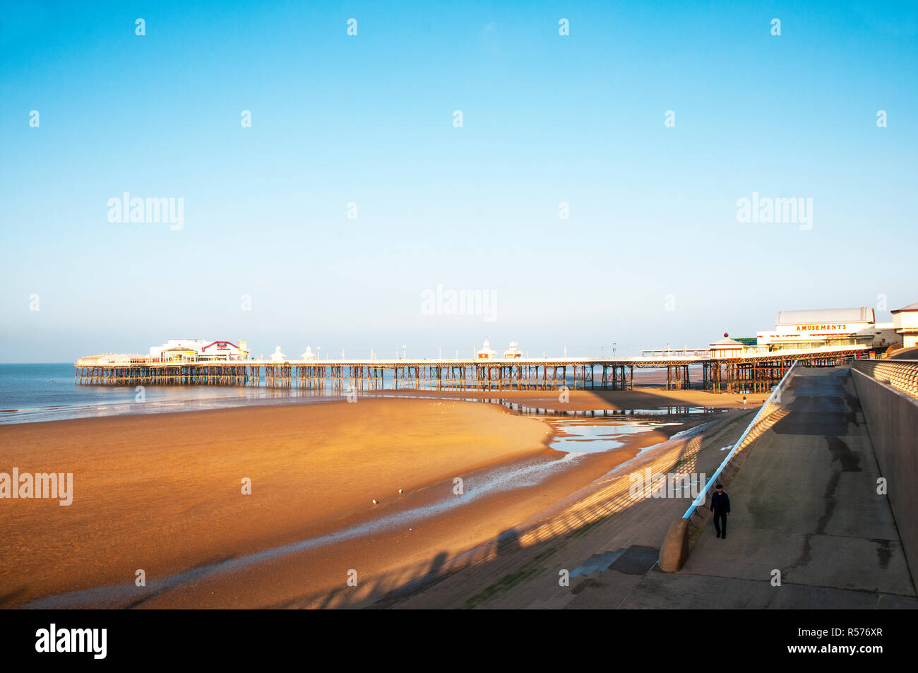 Blackpool North Pier und Golden Sands mit einem einsamen Person helling hinunter an den Strand. Lange Schatten durch niedrige Winter Sonnenlicht werfen. Stockfoto