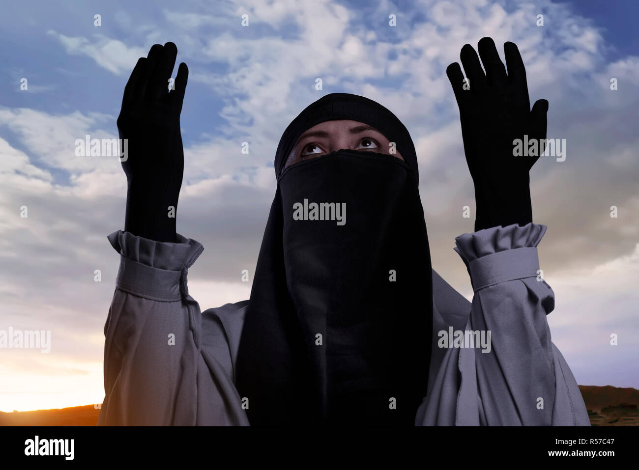 Religiöse asiatische Muslimin mit Kopftuch anheben Hand und Beten Stockfoto