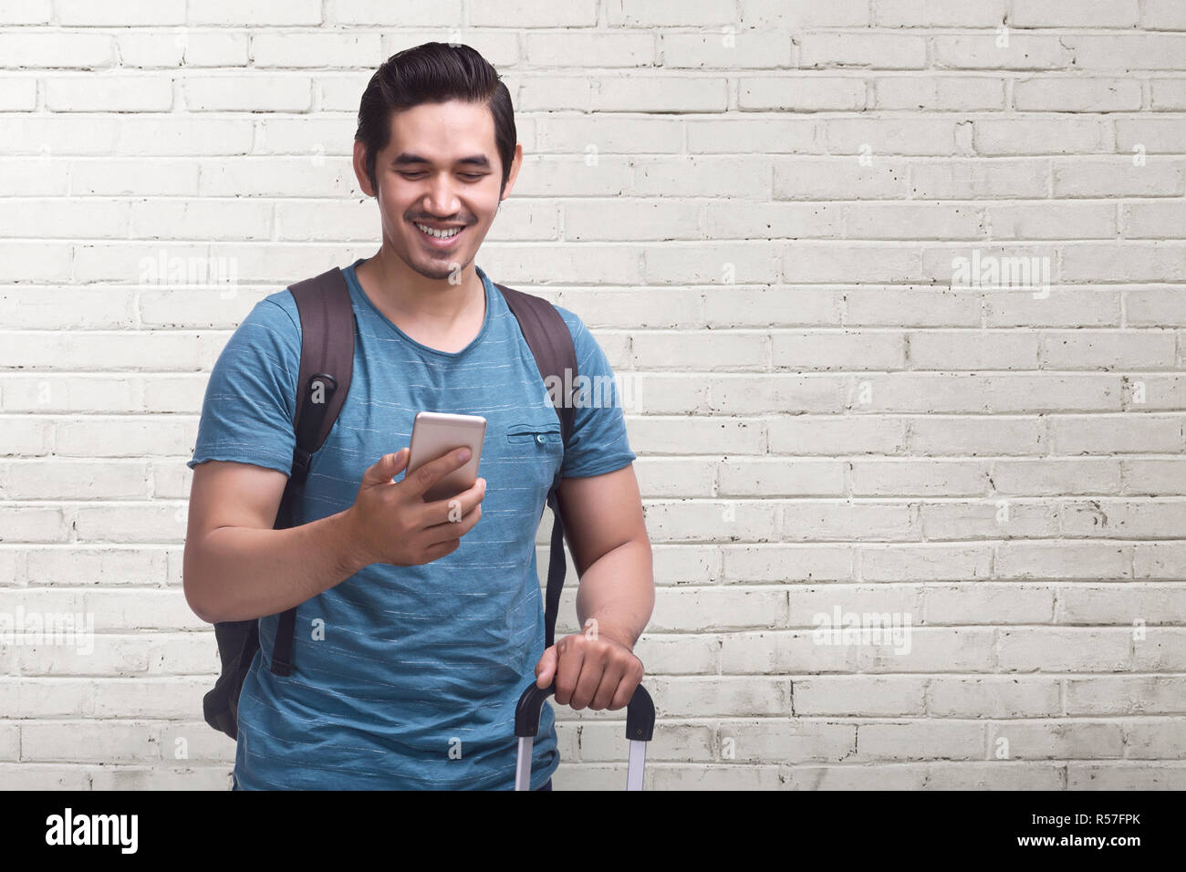Junge asiatischer Mann reise mit Handy mit Koffer Stockfoto