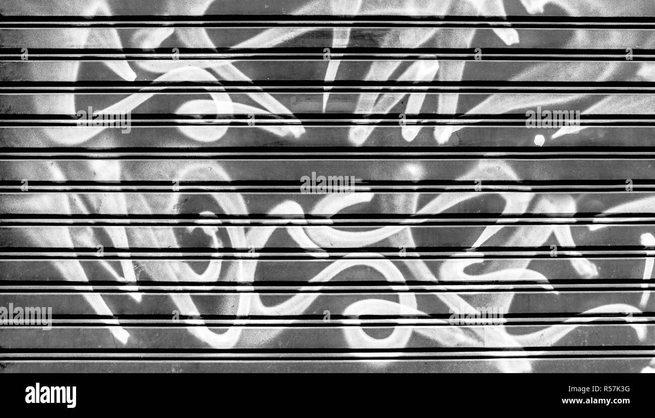 Schwarz Garagentor mit Vandalismus Zeichen von Graffiti weiß lackieren. Ideal für Konzepte und Hintergründe. Stockfoto