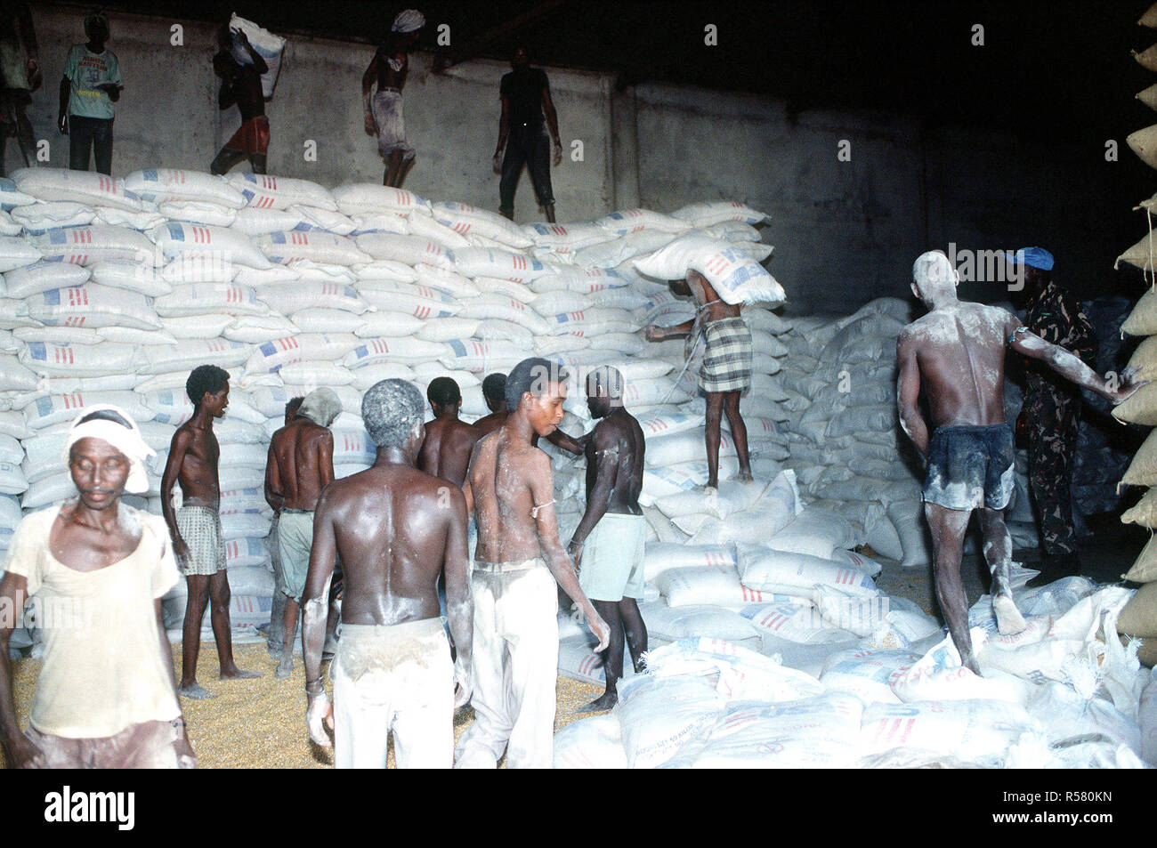 1993 - Somalische Männer arbeiten in einem Lagerhaus in Kismayo. Die Lieferungen werden geliefert, um die Verteilung von Nahrungsmitteln Zentren, die von einem belgischen Kontingent, das in Somalia zur Unterstützung der Operation weiterhin Hoffnung. Stockfoto