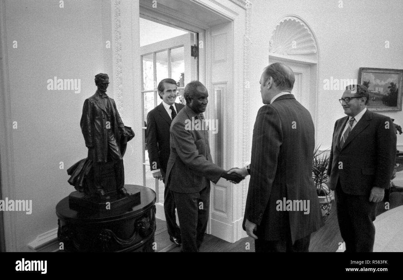 4/19/1975 - Foto von Präsident Gerald R. Ford, Außenminister Henry Kissinger, und Chef des Protokolls Henry Catto Begrüßung Präsident Kenneth Kaunda von Sambia im Oval Office Stockfoto