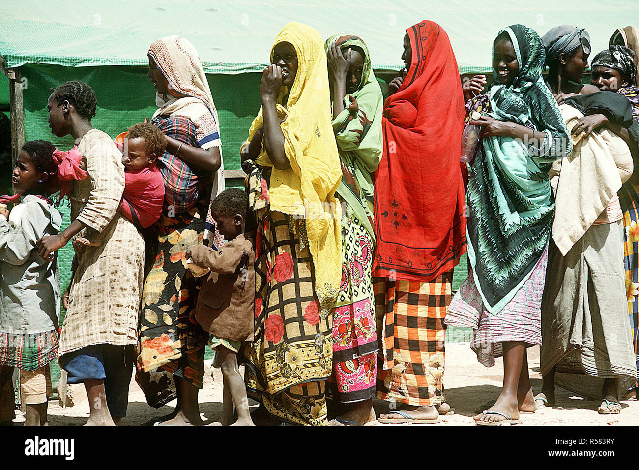 1993 - somalischen Frauen und Kinder Line up an eine Beihilfe Station während der multinationalen Entlastung Bemühung Operation Restore Hope. Stockfoto