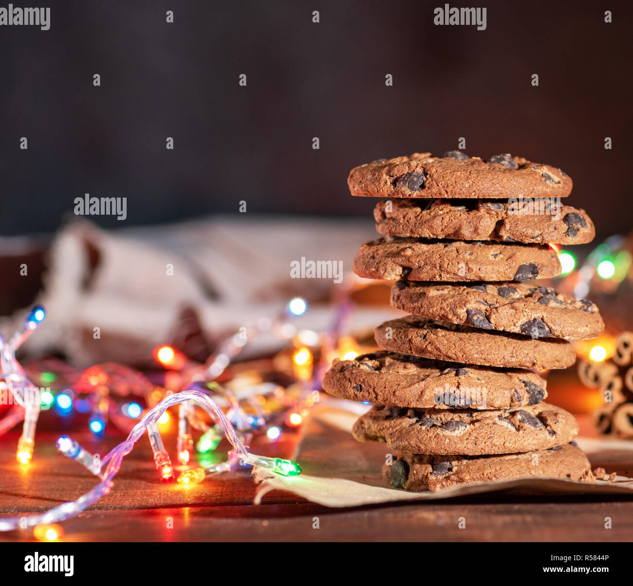 Runde Schokolade Cookies in einem Stapel, um brennende Girlanden des Neuen Jahres auf einem braunen Tisch Stockfoto
