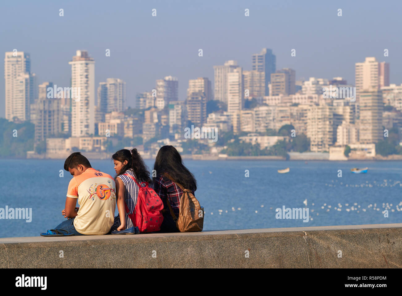 Studenten am Marine Drive, ein Boulevard entlang der Arabischen See in Mumbai, Indien, der "Posh" Bereich der Walkeshwar im Hintergrund Stockfoto