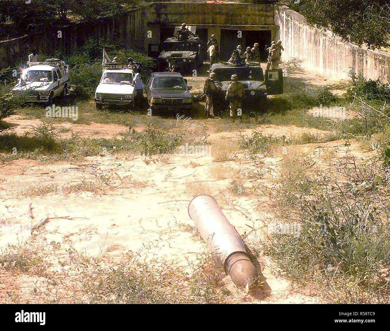 Der Eintritt einer Schätzungsweise 38 Bunker entdeckt, nördlich von Mogadischu, Somalia, von Abgeordneten aus den 511 . Military Police Company, Fort Drum, New York. Die MPs escort Mitglieder der Medien in den Bunker. Zwei M998 High-Mobility Multipurpose Radfahrzeuge (Hmmwv) nahe dem Eingang zusammen mit drei Fahrzeugen, die von den Medien Gefahren abgestellt sind. Eine große Unbekannte artillery Shell ist im Vordergrund gesehen. Diese Mission ist in der direkten Unterstützung der Operation Restore Hope. Stockfoto