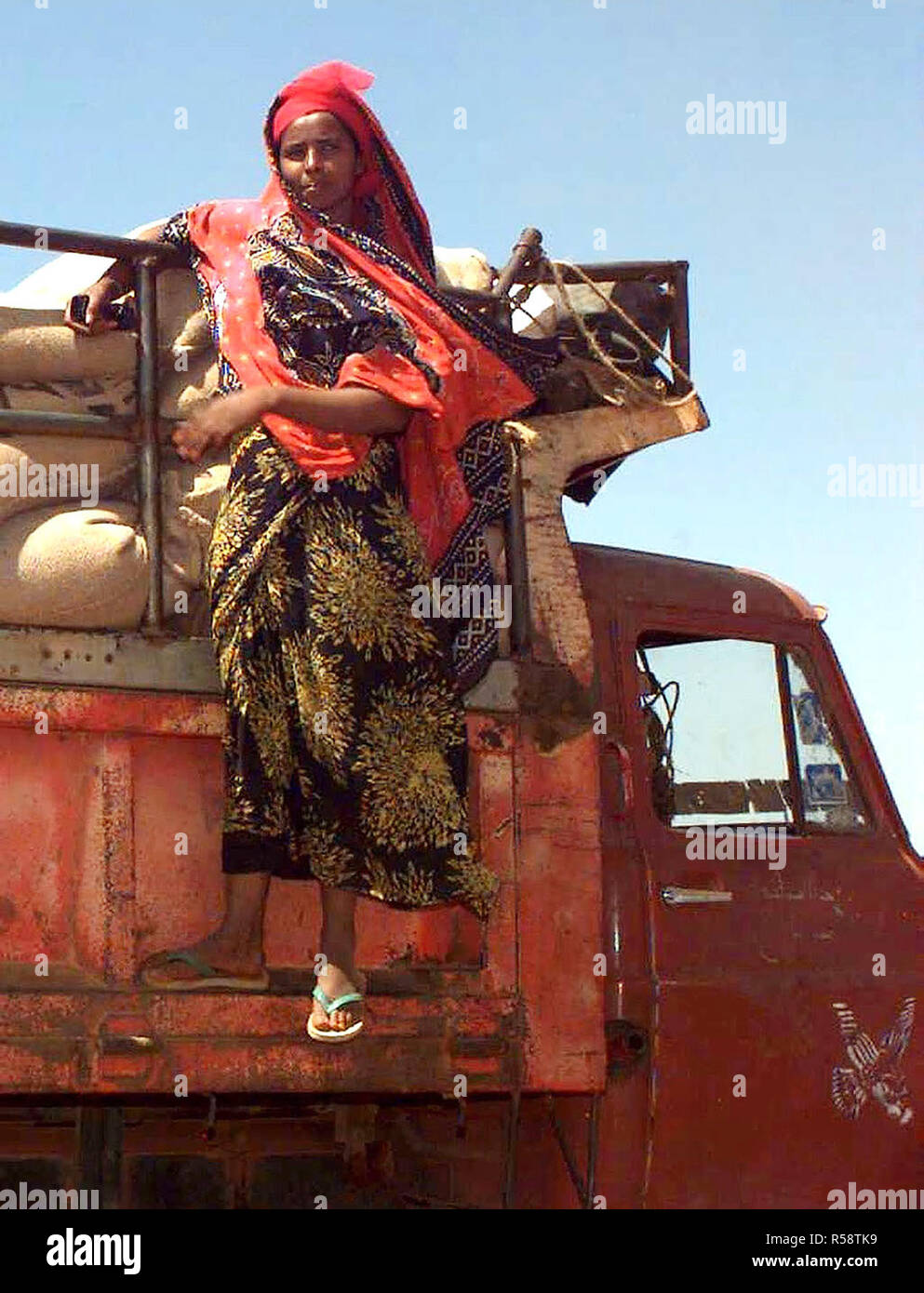 1993 - Gerade auf Schuß eines somalischen Frau auf der rechten Seite des dump Rack Klammern auf einem Isuzu Dump Truck. Sie beobachtet die Männer laden Sie die Säcke Weizen gespendet, die von den Menschen in Australien (nicht abgebildet). Diese Mission ist in der direkten Unterstützung der Operation Restore Hope. Stockfoto