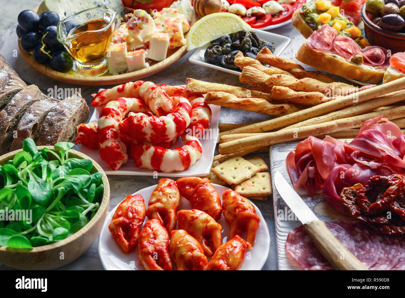 Italienische Antipasti Snacks. Brushettas, Käse Vielfalt, Garnelen, Lachs, Oliven, Schinken mit Birne, Salami und Schinken über Graues grunge Tabelle, oben Stockfoto