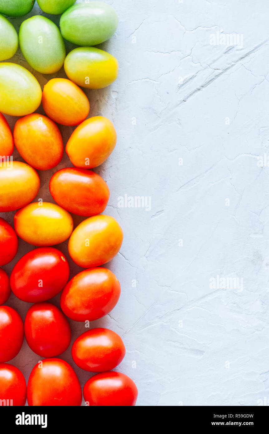 Farbenfrohe Tomaten auf einen weissen Stein Hintergrund. Overhead v Stockfoto