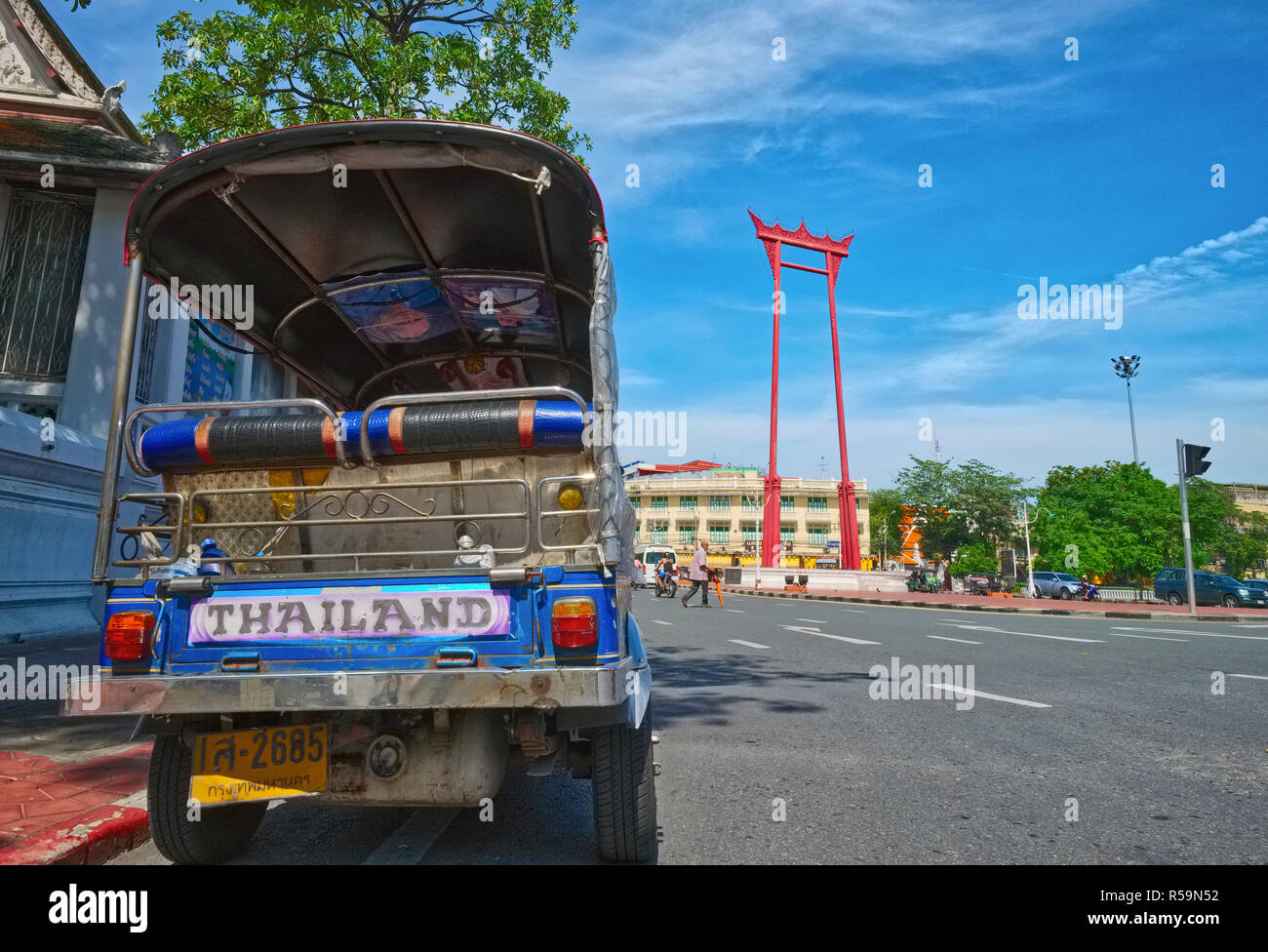 Ein typisches thailändisches Tuk-Tuk- oder Dreirad-Taxi, prunkvoll mit der Bezeichnung „Thailand“ gekennzeichnet, steht zwischen dem Giant Swing und dem Wat Suthat in Bangkok, Thailand, auf dem Parkplatz Stockfoto