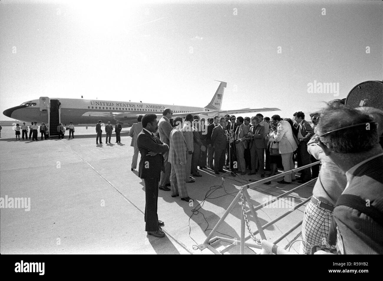 1976, April - Andrews Air Force Base - Henry Kissinger, kenianische Beamte (evtl. 3 kenianischen Mitglieder des Kabinetts), Medien, Geheimdienst - stehend auf dem Asphalt; Henry Kissinger am Mikrofon sprechen zu drücken - Staatssekretär Reise nach Afrika; Abfahrt Flughafen; Erläuterungen zu drücken Stockfoto