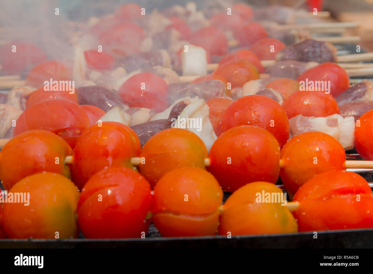 Huhn Herzen mit Tomate und Zwiebel kochen auf heißen Grill Stockfoto