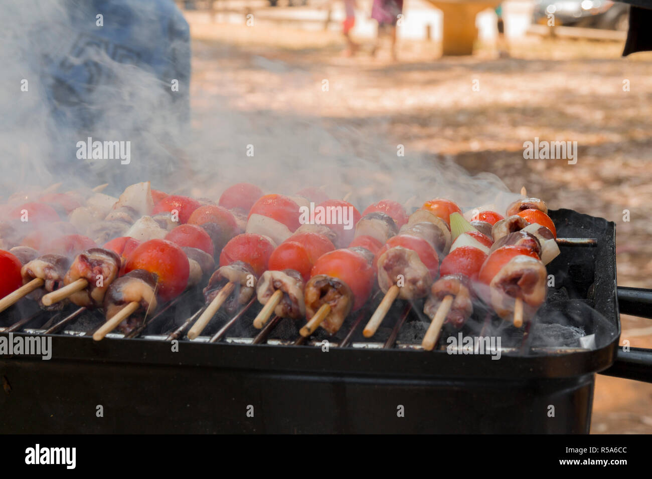 Huhn Herzen mit Tomate und Zwiebel kochen auf heißen Grill Stockfoto