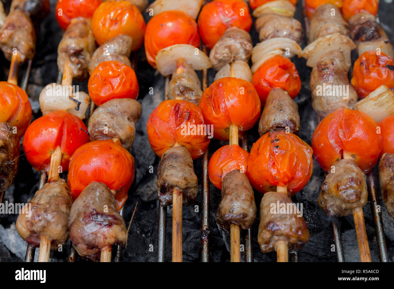 Huhn Herzen mit Tomate und Zwiebel kochen auf heißen Grill Stockfoto
