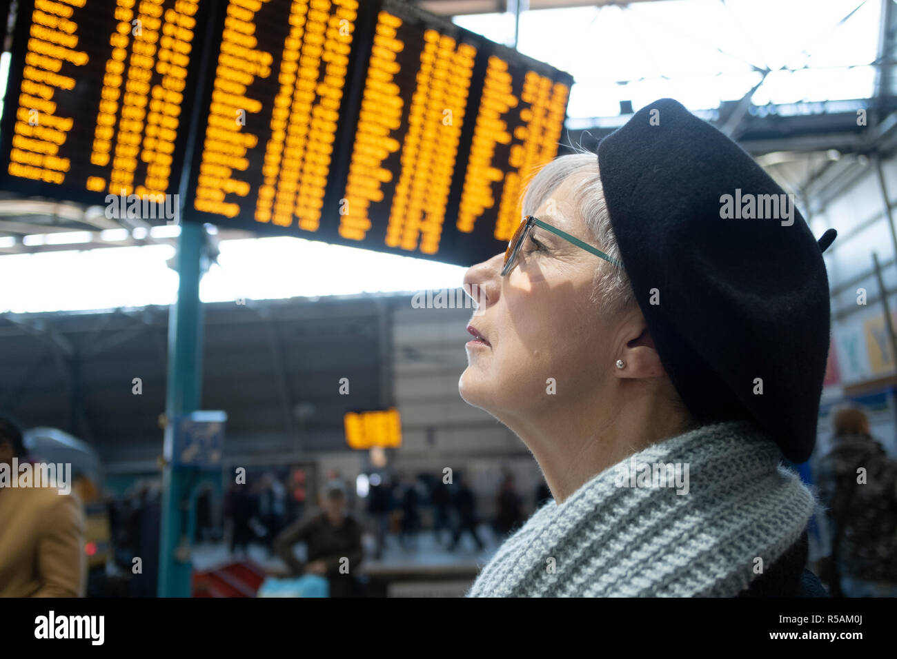 Ältere Frau an zugfahrplan Ansagenbaugruppe suchen Stockfoto