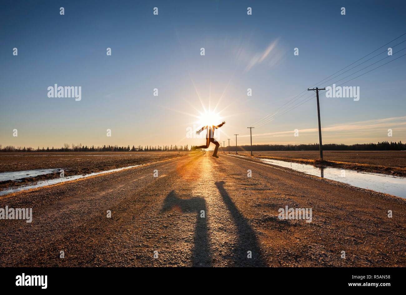 Man überspringt den Straße mit Sonne über seinem Kopf Stockfoto