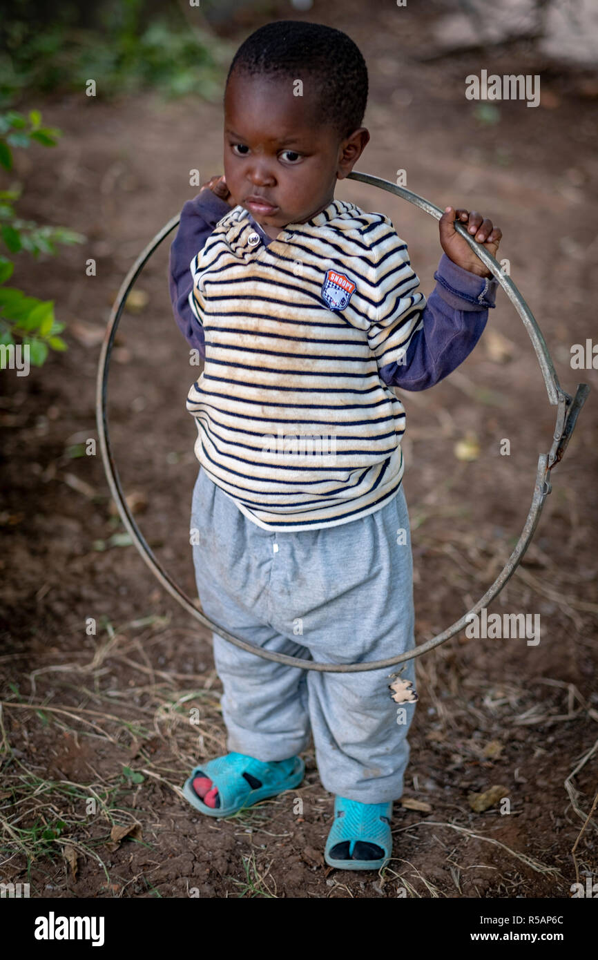 Portrait einer entzückenden jungen tansanischen Jungen von 3 Jahren spielen mit einem Hoop in seinem Hof Stockfoto