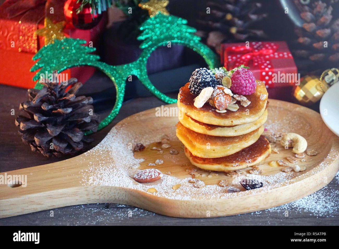 Pfannkuchen mit Beeren und Mutter mit Hintergrund Geschenk und Pine Cone unter Weihnachtsbaum, Holiday Party Dessert. Pfannkuchen mit Beeren und n Stockfoto