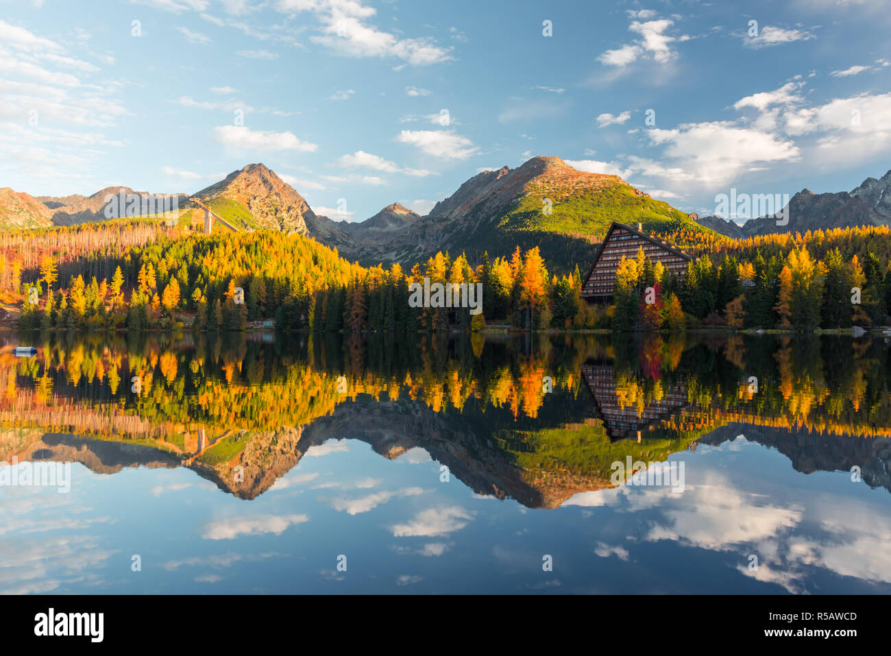 Malerischer herbst Blick auf den See Strbske Pleso in der hohen Tatra, Slowakei. Klares Wasser mit Reflexionen von orange Lärche und hohe Berge Stockfoto